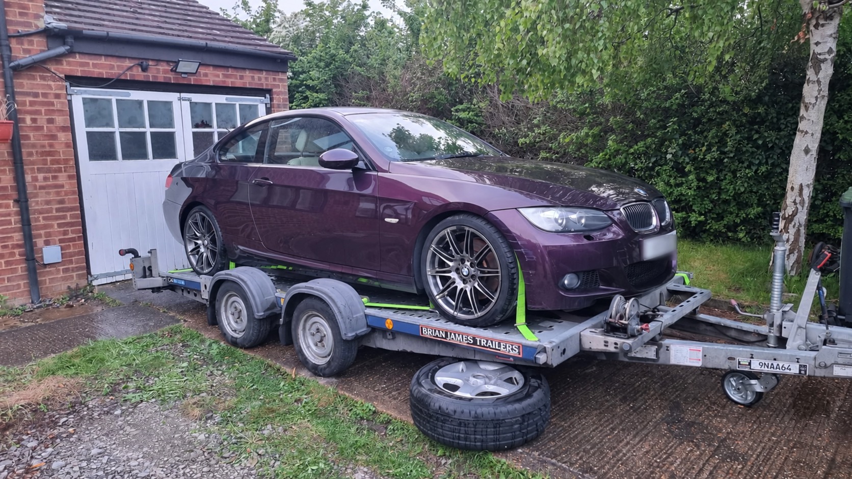 Car transporter trailer carrying a purple car, with its registration plate obscured